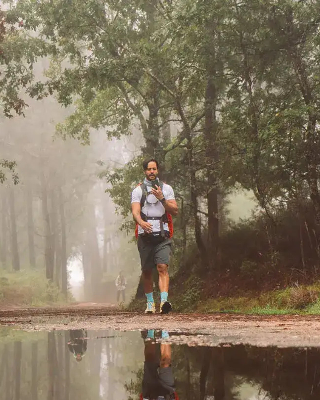 Samir Abud caminhando por uma trilha na floresta com neblina